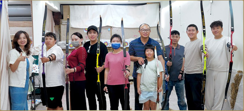 十位學員在貓小隊室內射箭場手持反曲弓的團體合照